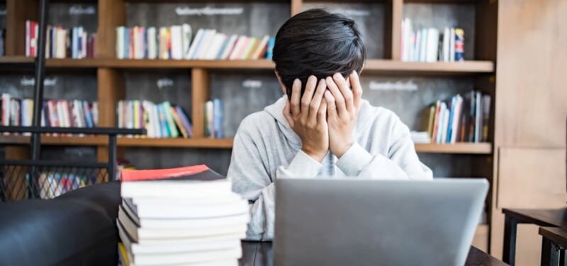 hombre joven estudiante computadora sentado en la mesa con ansiedad